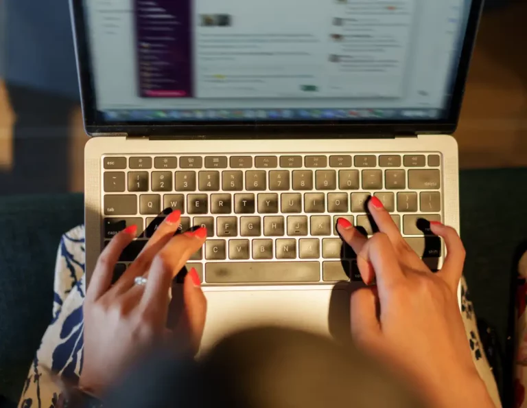 close up of woman hands typing on laptop in cafe